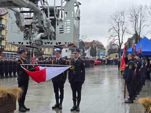 Służby mundurowe trzymające flagę.