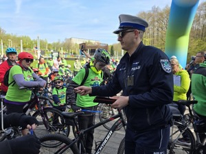 Policjant wręczający odblaski uczestnikom rajdu.