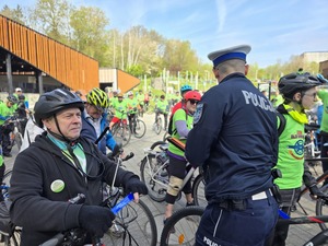 Policjant wręczający odblaski uczestnikom rajdu.
