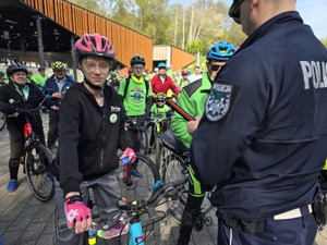 Policjant wręczający odblaski uczestnikom rajdu.
