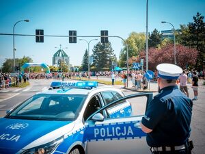 Radiowóz policyjny oraz policjant podczas zabezpieczenia biegu oraz uczestnicy.