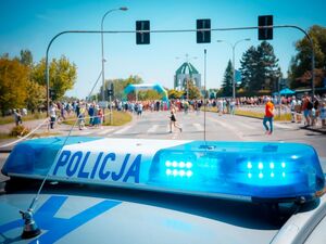 Radiowóz policyjny podczas zabezpieczenia biegu oraz uczestnicy.
