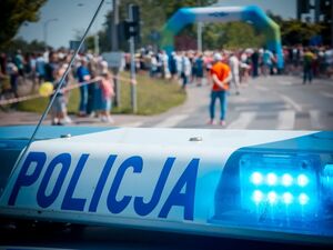 Radiowóz policyjny podczas zabezpieczenia biegu oraz uczestnicy.