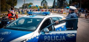 Radiowóz policyjny oraz policjant podczas zabezpieczenia biegu.
