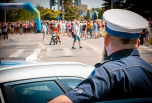 Radiowóz policyjny oraz policjant podczas zabezpieczenia biegu.