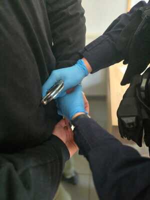 Zatrzymany oraz policjant zakładający mu kajdanki.