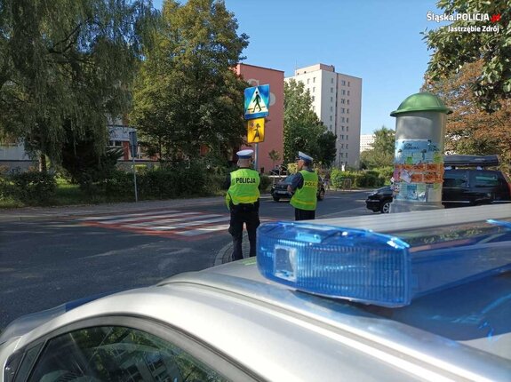 Policjanci drogówki stojący przy przejściu dla pieszych.