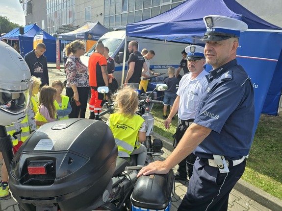 Dzieci oraz policjanci przy motocyklu służbowym.