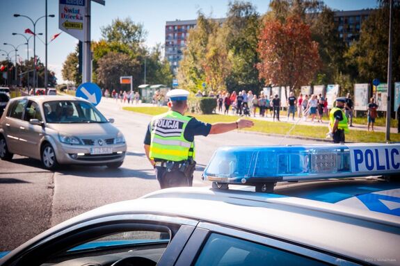 Policjant na skrzyżowaniu w trakcie zabezpieczenia przejazdu.